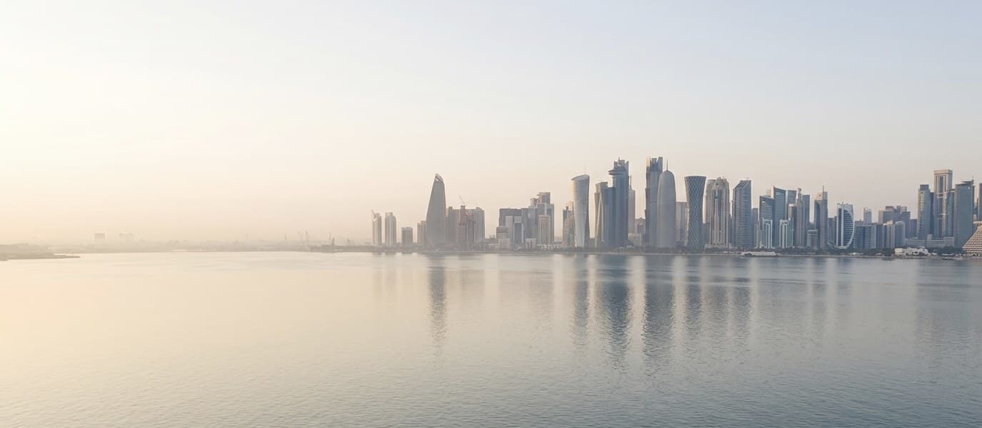 Doha skyline and waterfront corniche at dawn.